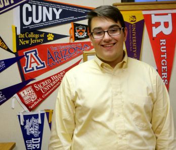 Anthony Hubner ’17 stands in front of the various pennants in the College Placement Office.