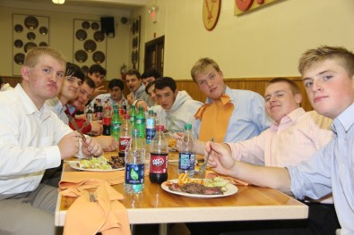 A group of seniors makes comical faces for the camera while enjoying sugary drinks, steak, and fries.