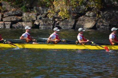 Members of the varsity eight boat intensely row, seeking victory.