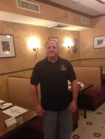 Bob Bernam, owner of Plum Tomatoes pizzeria, stands near some of the restaurant’s seating.
