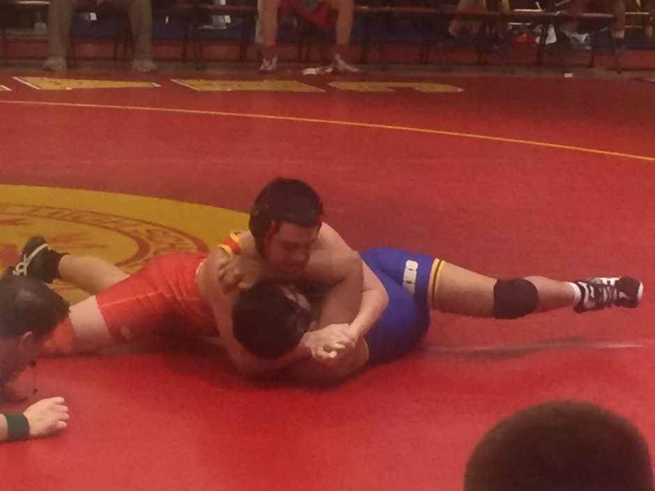 One of the crimson and gold grapplers lifts up his adversary’s head in attempt to finalize his pinning combination. 
