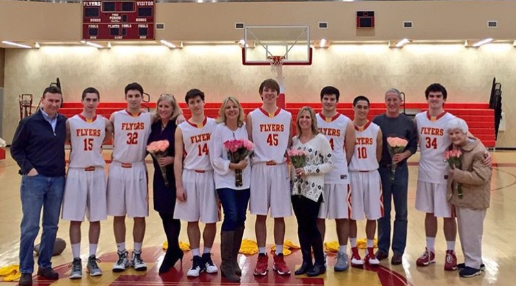 Senior members of the Varsity basketball team gather around with their parents or grandparents for the team’s Senior Night.