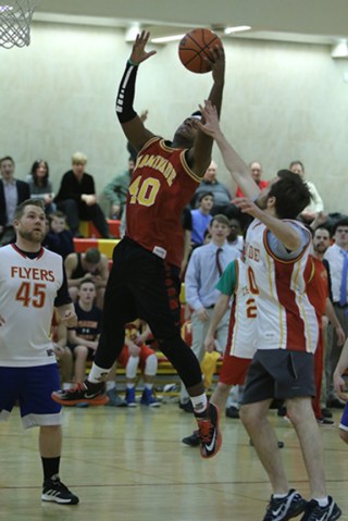 Tyler Toussaint ’16 jumps up to shoot a layup while Mr. Sebastian Agosti ’09 attempts to block his path to the net.