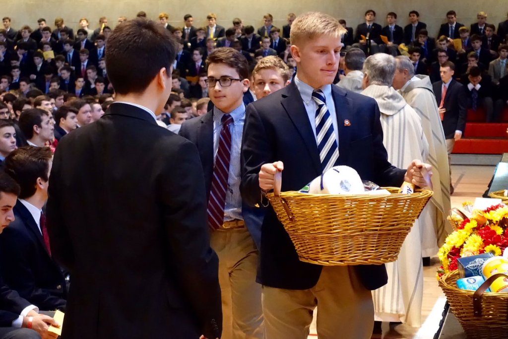Nicholas Milano ’17 places a basket filled with toiletries on the altar prior to Communion.